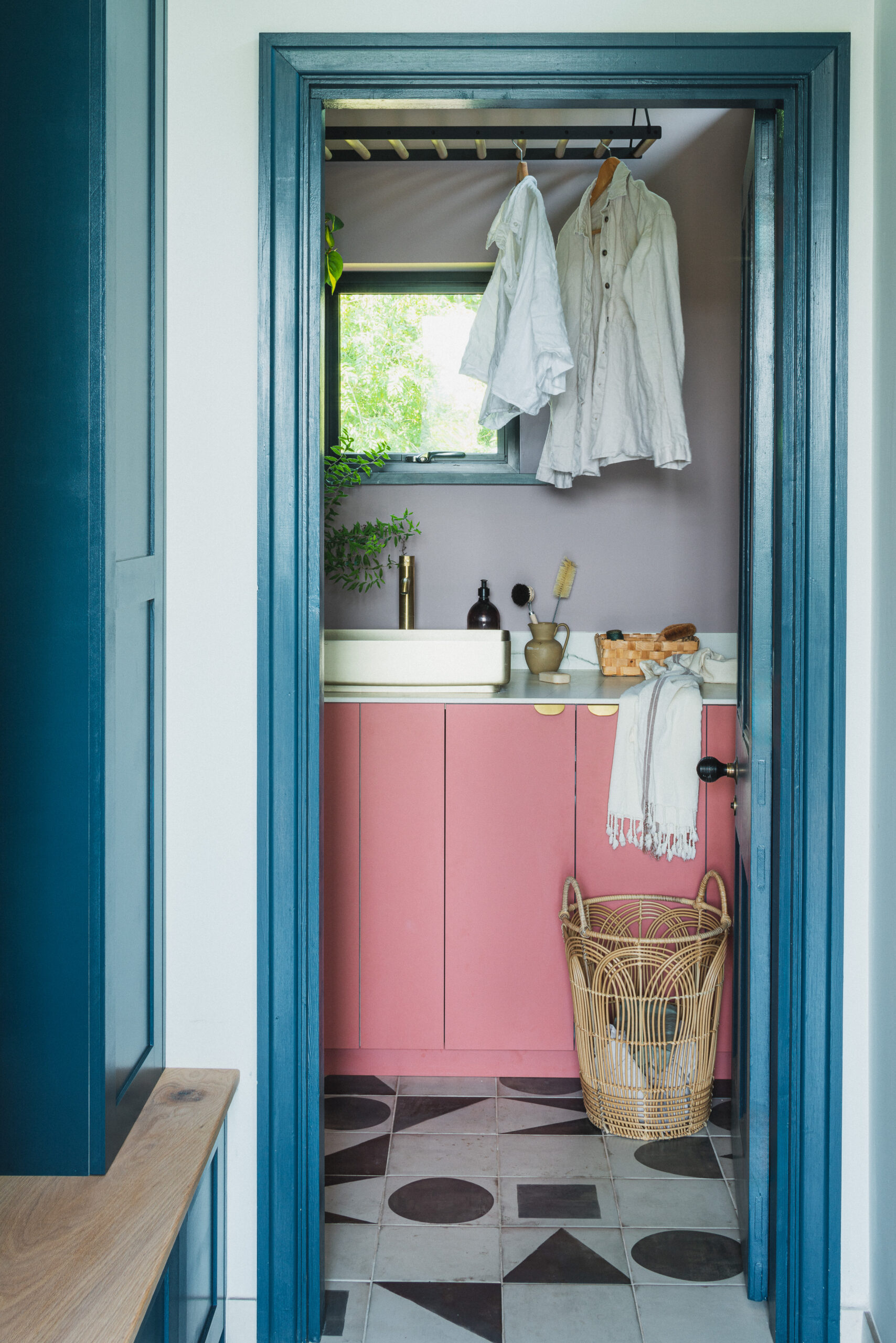 The utility room in Made by HUSK's Goldney Lodge Kitchen, featuring pink fronts and an off white worktop.