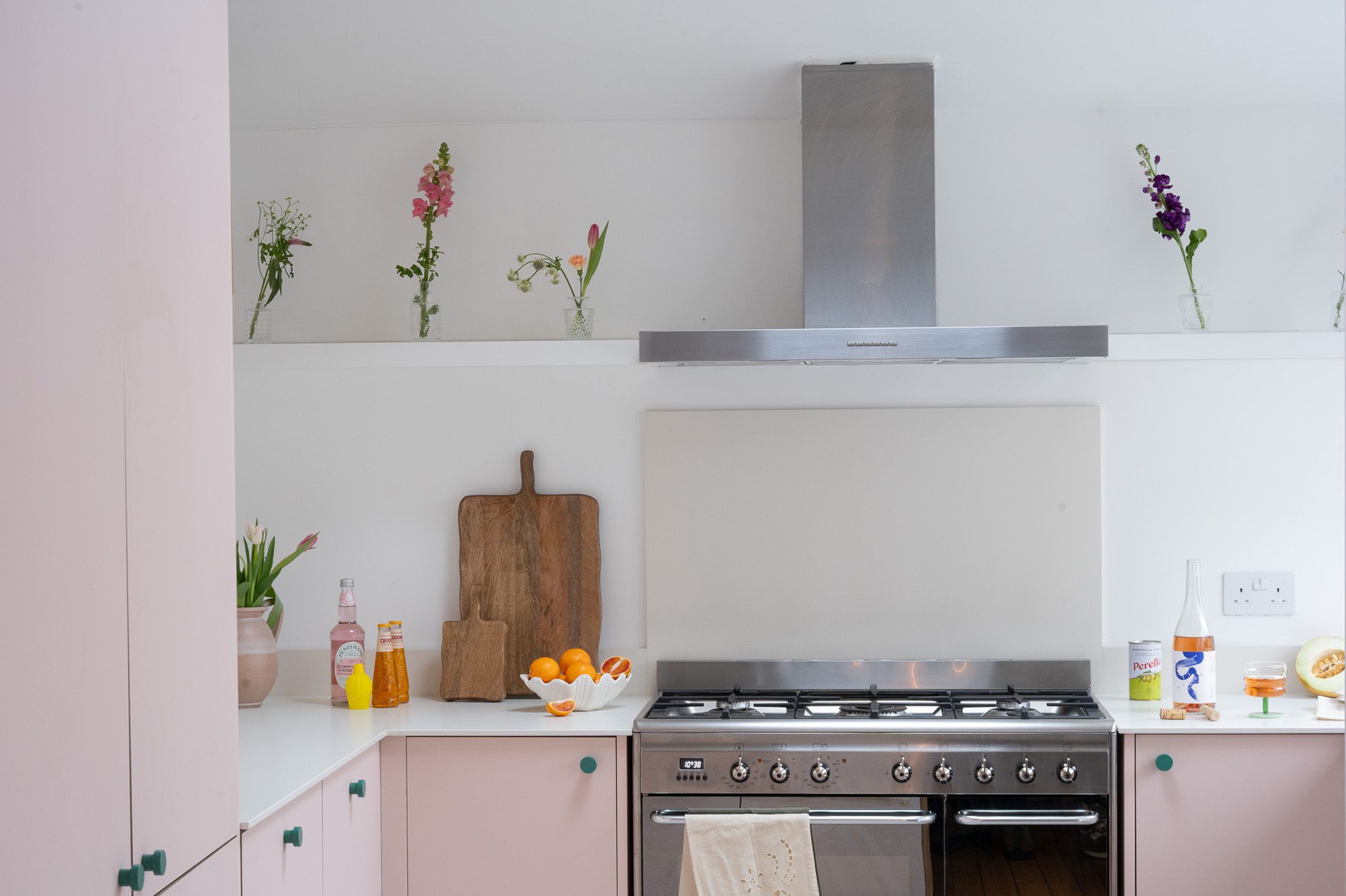 A bright kitchen with pink fronts and a white marble worktop.