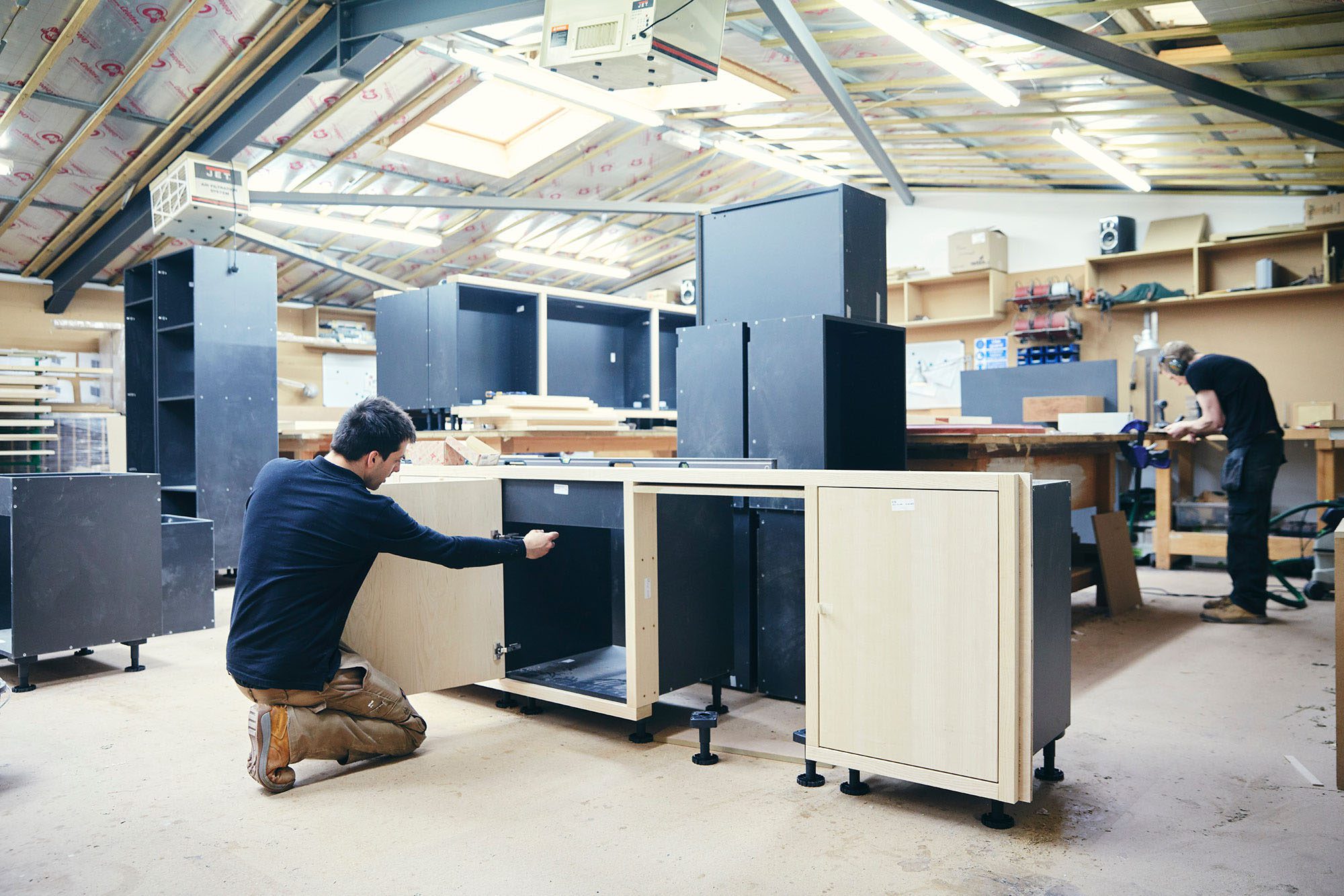 Image of two men working on kitchen cabinets in HUSK's Montpelier, Bristol workshop.