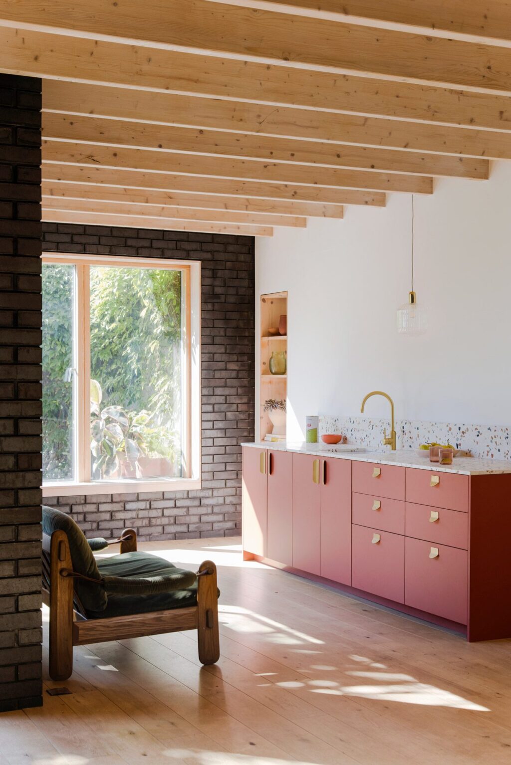 Mid-century pink and brown modern kitchen with terrazzo worktops and exposed beam ceiling.