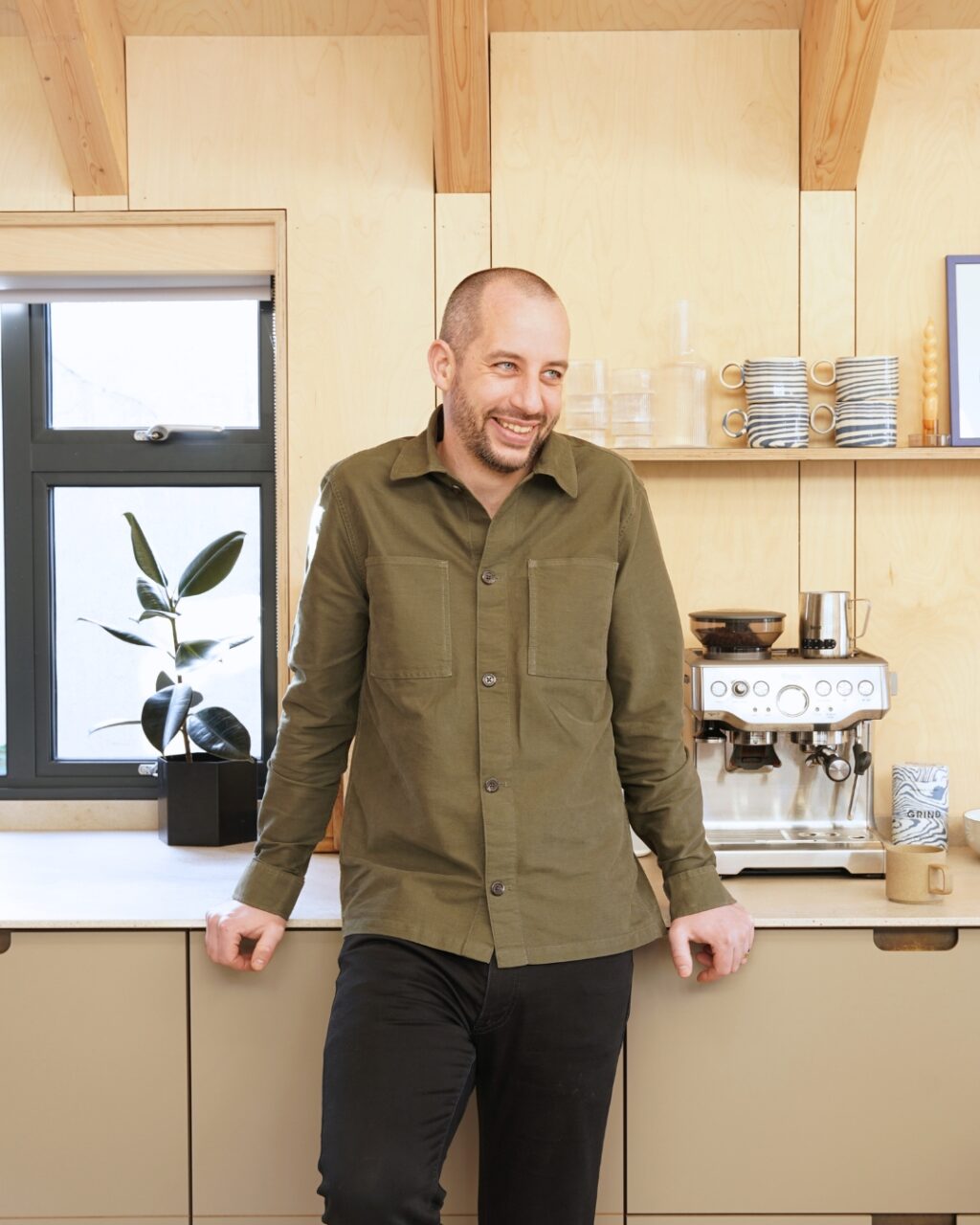 Man smiling and leaning against kitchen cabinets