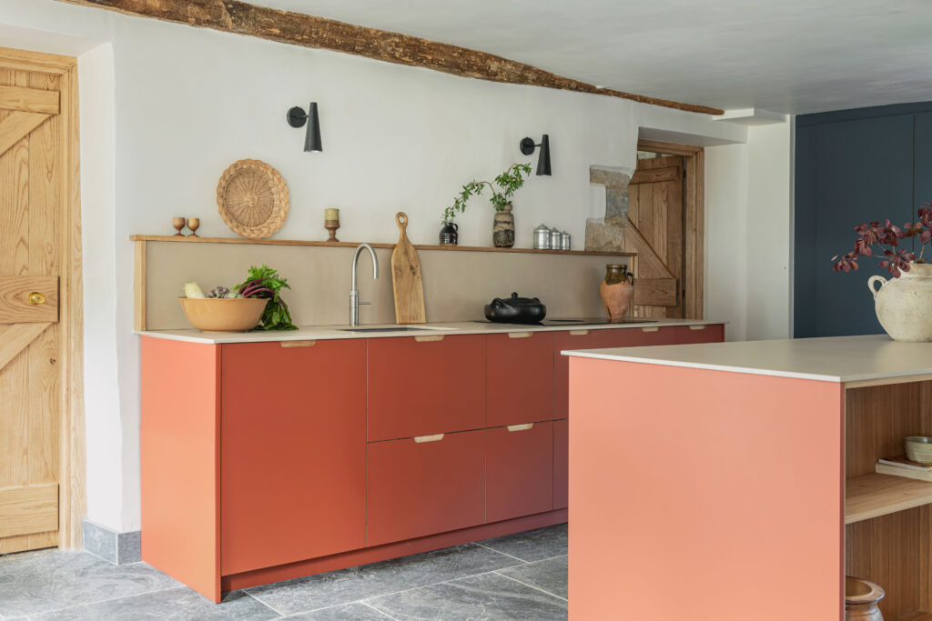 Modern terracotta kitchen featuring a rustic oak wooden door, a wooden kitchen island with slate floors
