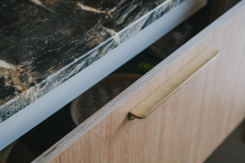 A plywood kitchen cabinet edge with a brass handle