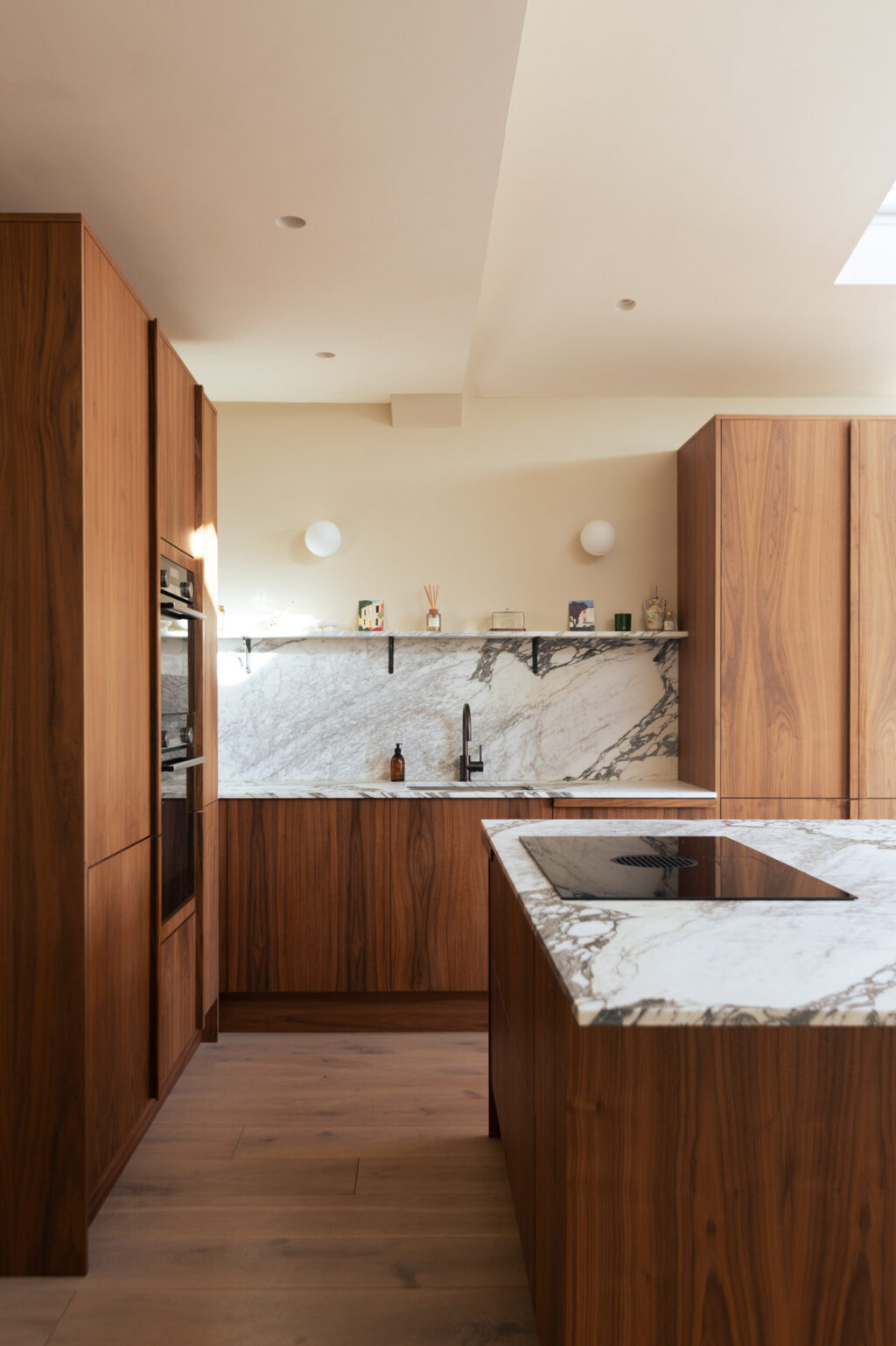 Contemporary walnut and marble kitchen with large island and built-in appliances, custom cabinetry by HUSK Bristol.