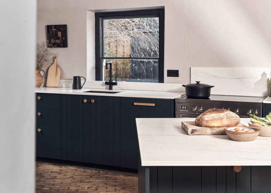 Full kitchen view with dark green ash veneer cabinets, marble worktops and range cooker, modern bespoke kitchen