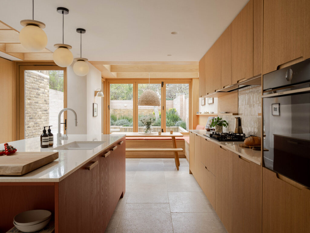 Oak veneer kitchen cabinetry with integrated Bosch appliances, terrazzo worktops and Devon Red island with exposed shelving