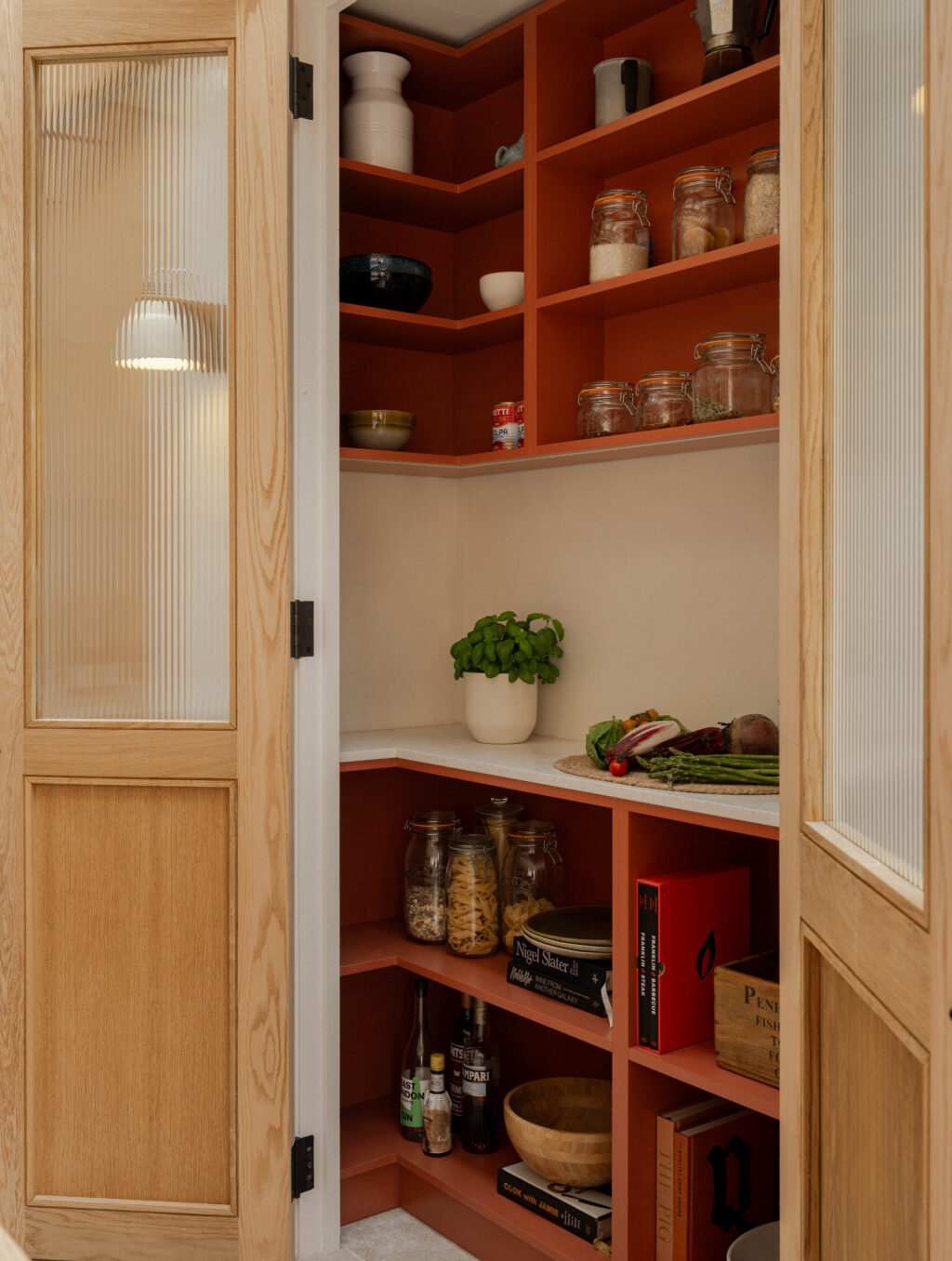 Corner pantry detail with red shelving, reeded glass oak framed doors and integrated terrazzo preparation surface