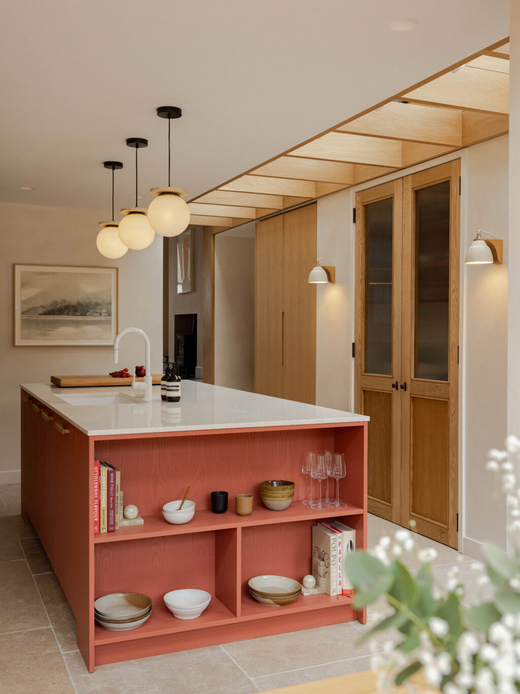 Kitchen island with open shelving in HUSK x Another Country Devon Red Fallow finish, terrazzo worktop and Natural Oak Veneer pantry cabinetry with ply edge