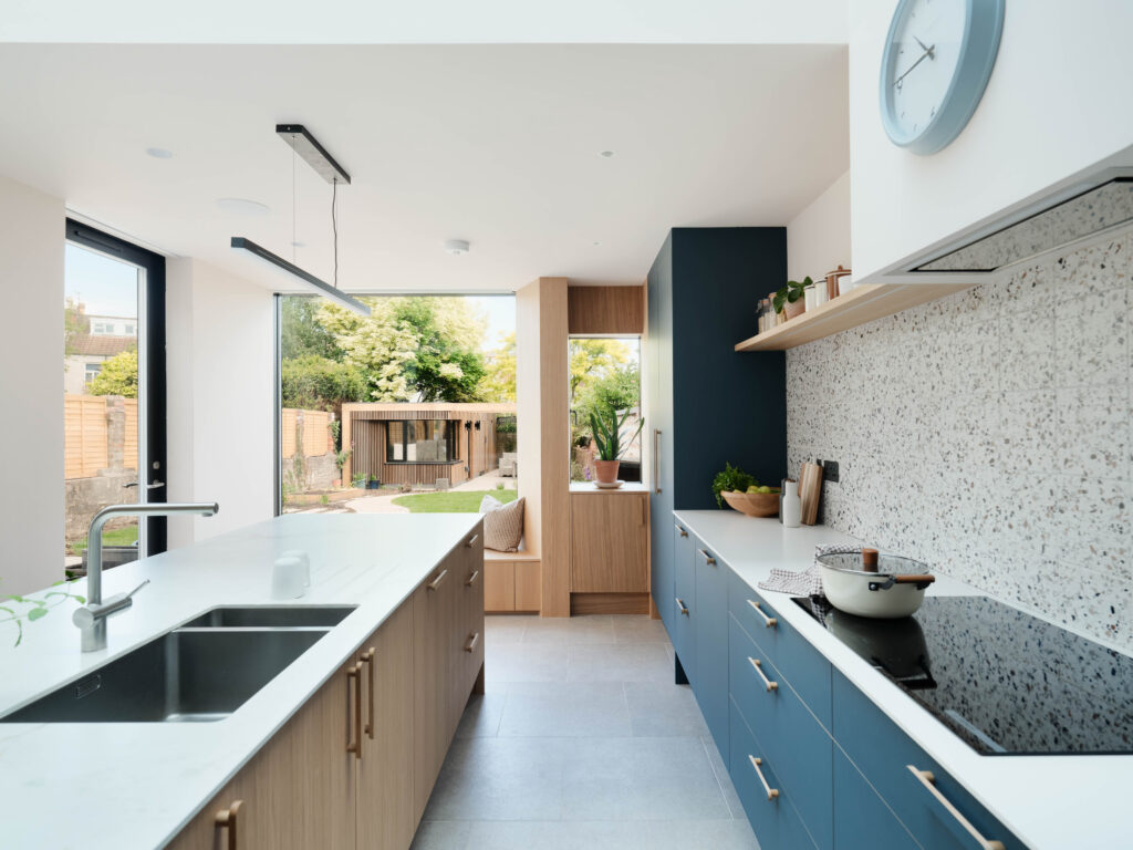 Open-plan kitchen with FENIX Blu Shaba cabinetry, oak island and expansive glazing connecting the interior to the garden.