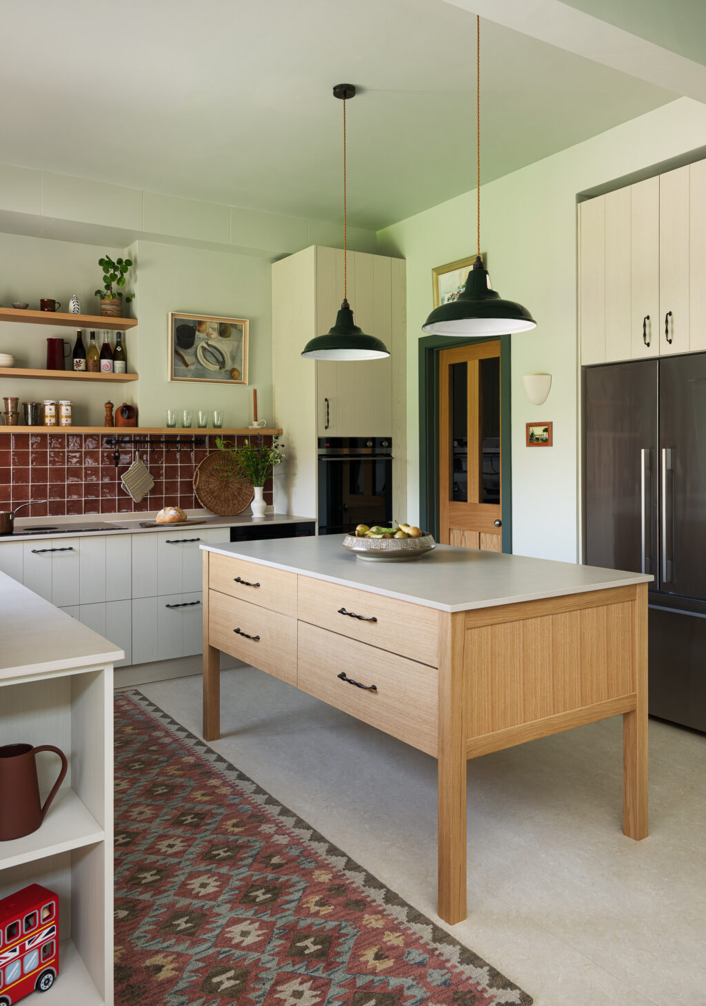 Oak kitchen island with blackened bronze handles, patterned runner rug and bespoke Purbeck Grey cabinetry