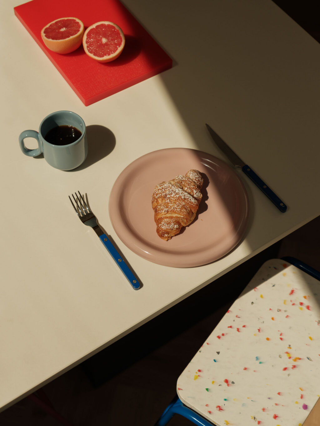 Croissant, coffee and grapefruit arranged on a Neolith Just White island showcasing the kitchen's bright, playful colour palette.