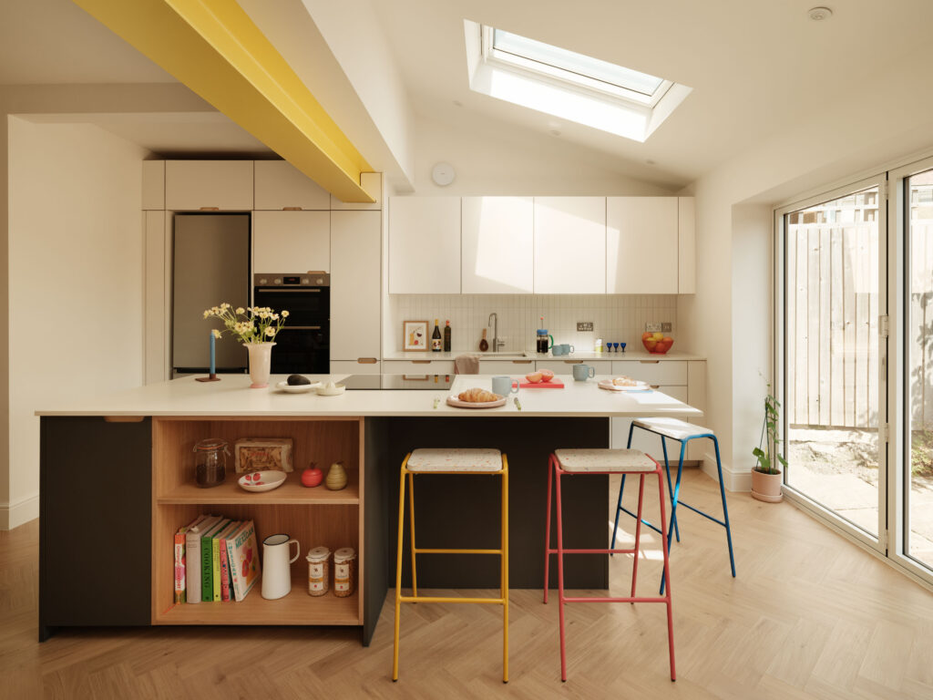 The St George Kitchen featuring a FENIX Bianco Male and FENIX Grigio Aragona kitchen with natural oak open bookcase island, exposed ply scallop handles and colourful bar stools.