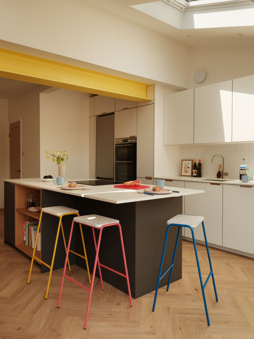 The St George Kitchen showcasing a yellow RSJ beam, FENIX Bianco Male cabinetry, FENIX Grigio Aragona island and colourful breakfast bar seating.