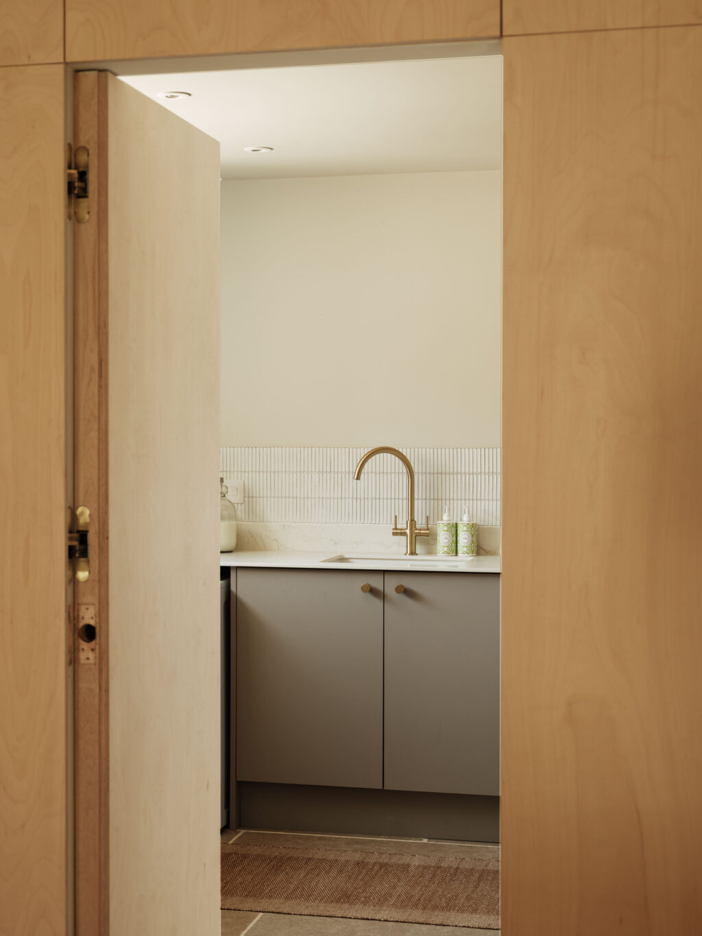 Utility room combining FENIX Beige Arizona cabinetry, exposed ply edging, generous worktop space and dedicated laundry storage.
