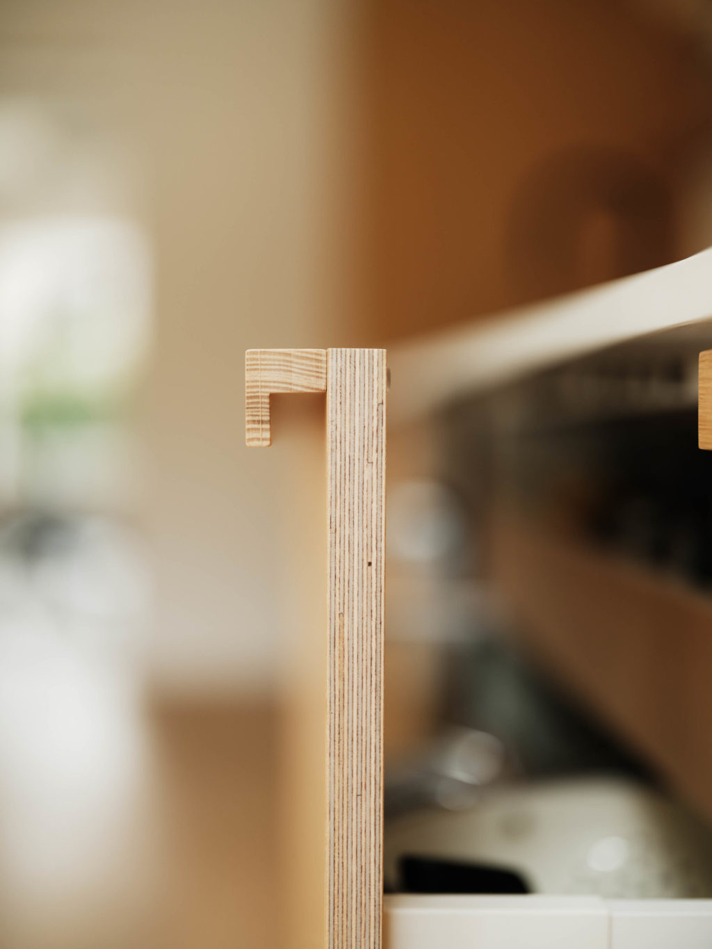 Detail of the solid oak L handle and exposed ply edge on an open kitchen drawer.
