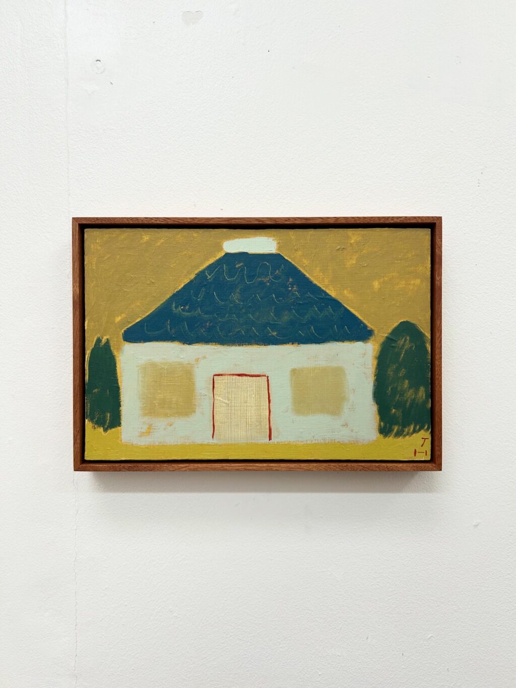 Framed Jay Harper painting of a small white house with a blue roof, set against a warm yellow background.